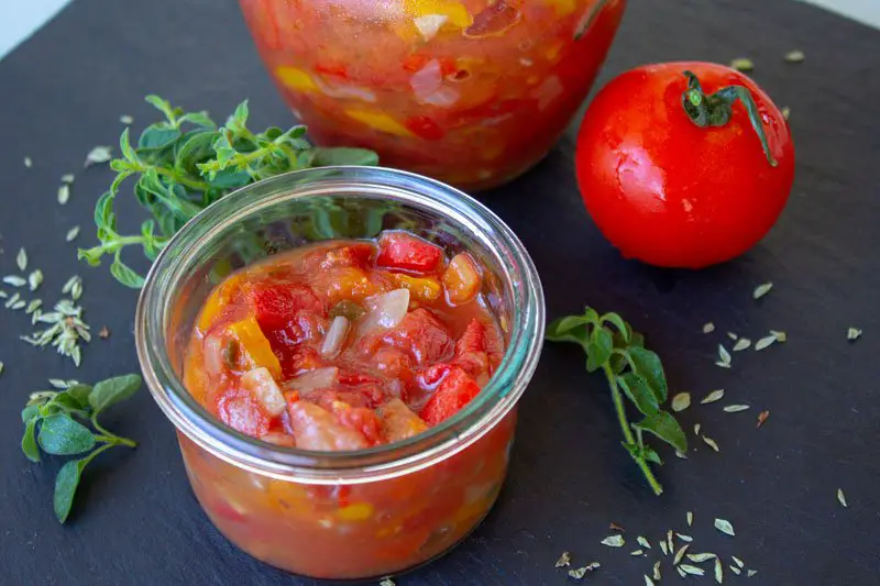 Bocal de compotée de tomates et poivrons avec les légumes et l'origan