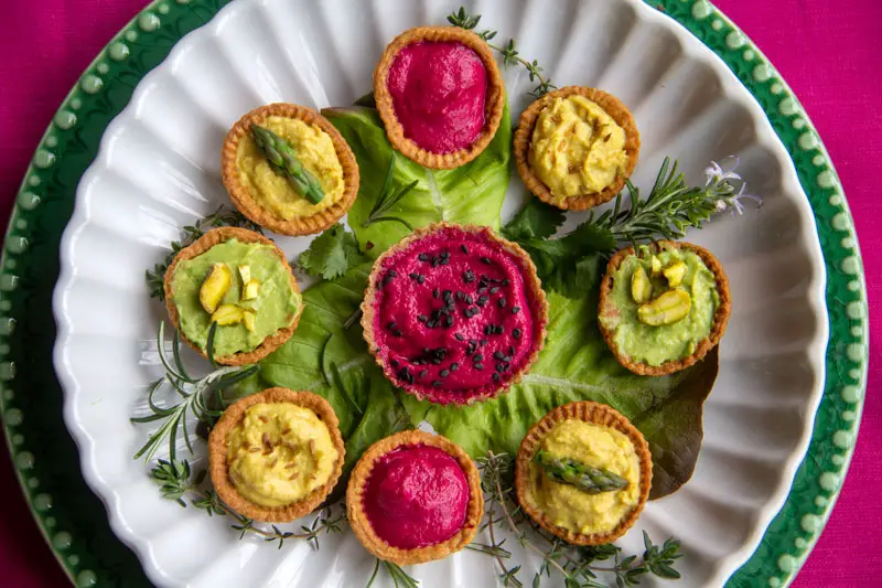 Assiette de mini tartelettes végétariennes sur fond rose