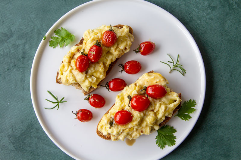 Assiette aux tartines d’œufs brouillés et petites tomates cerises
